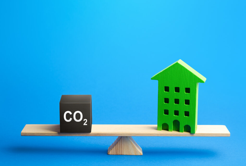 CO2 Baustein und grünes Haus halten sich auf Holz die Waage