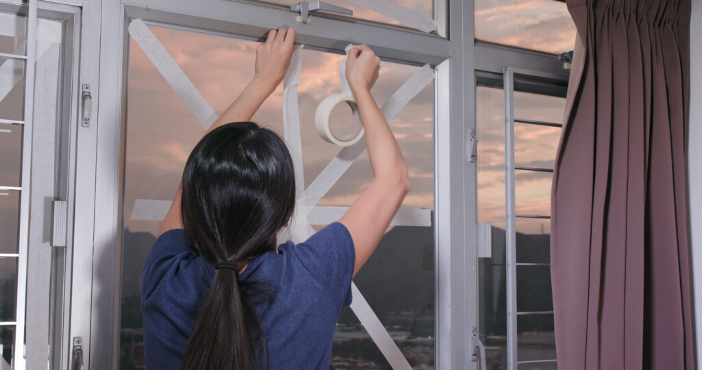 Frau beklebt Fenster mit Klebeband