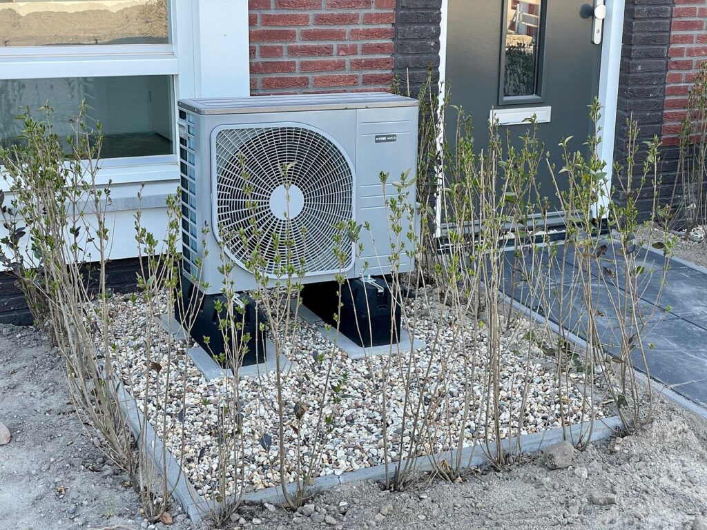 Eine neu installierte Wärmepumpe vor einer frisch gedämmten Hausfassade zeigt, wie die Förderung für den Heizungstausch ab 2027 wirkt – Foto: HarmvdB / Pixabay